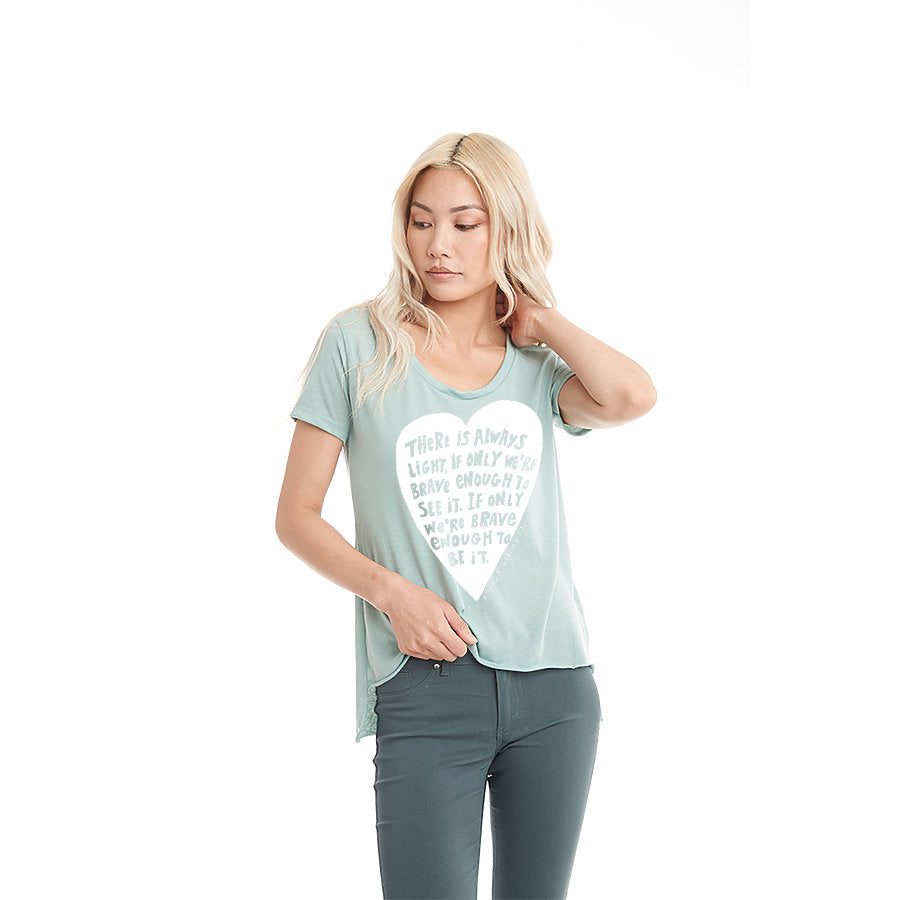 A woman wearing a light blue t-shirt with a white graphic design stands against a white background.
