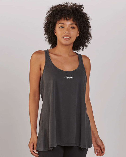 A young woman with curly hair wearing a gray tank top with the word "breath" printed on it.
