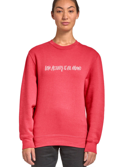 A woman wearing a red sweatshirt with the text "Love actually is all around" printed on it.