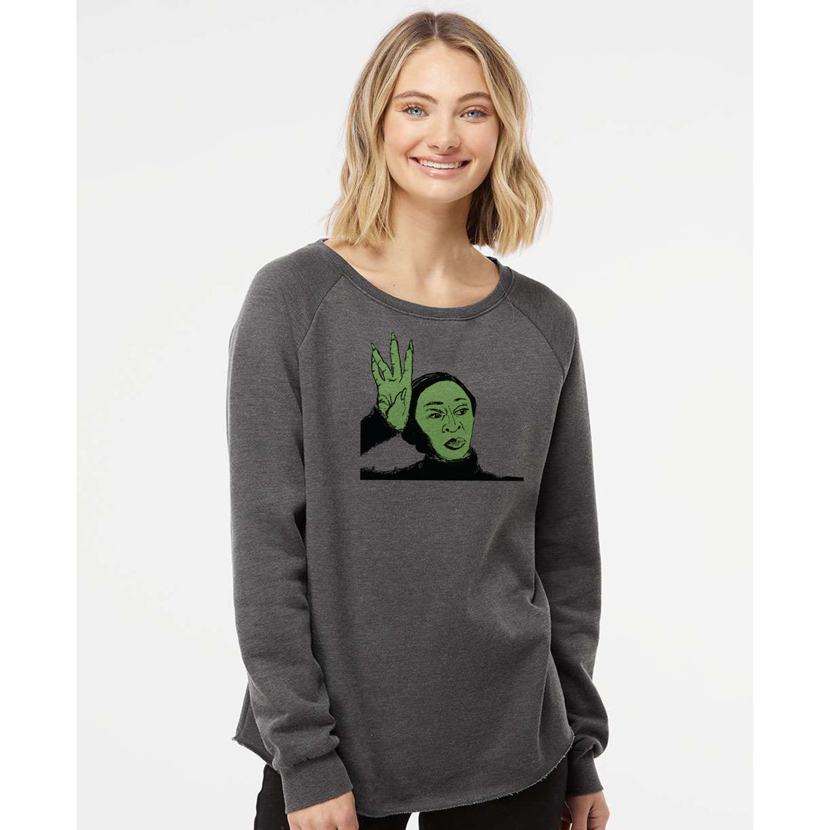 A woman wearing a gray sweatshirt with a graphic of a green-faced character on it, smiling at the camera.
