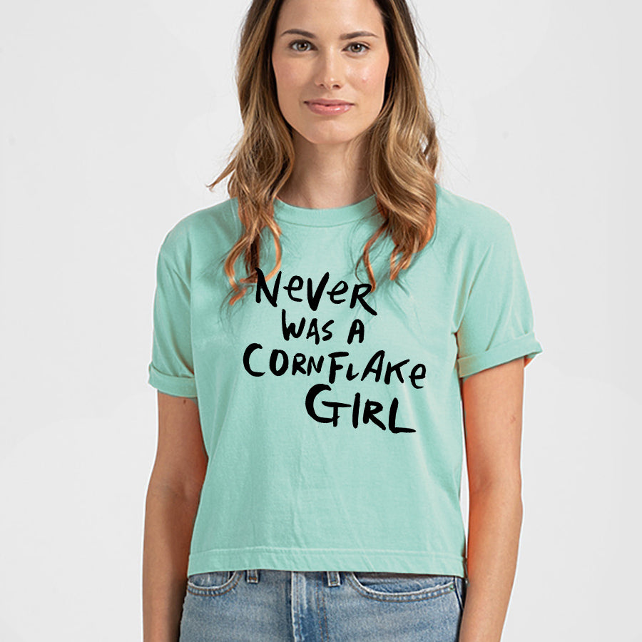 A woman wearing a mint green crop top with the text "Never was a cornflake girl" printed on it.