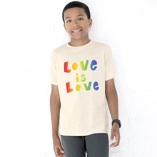 A young boy wearing a white t-shirt with the text "Love is Love" printed on it.
