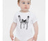 A baby wearing a white onesie with a black cat graphic on it.