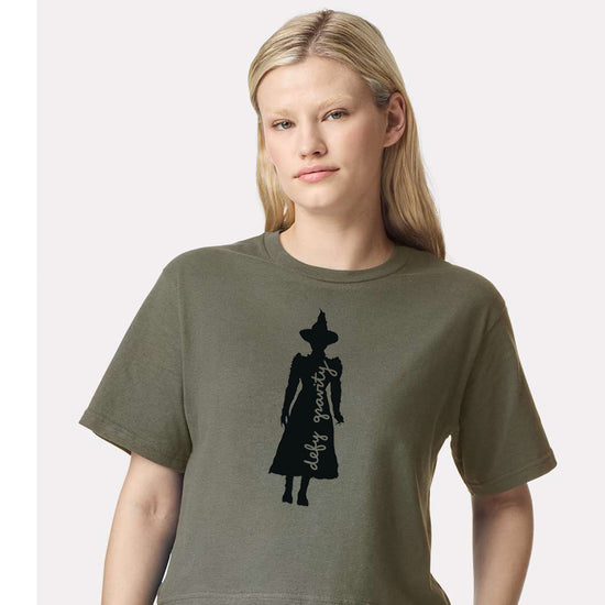 A woman wearing a green t-shirt with a silhouette of a person wearing a hat printed on it.