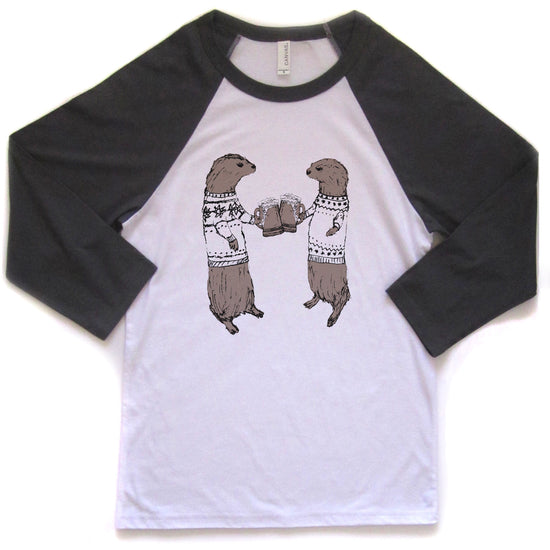 A white and black baseball-style t-shirt with a graphic design of two otters wearing sweaters and holding beer cans.