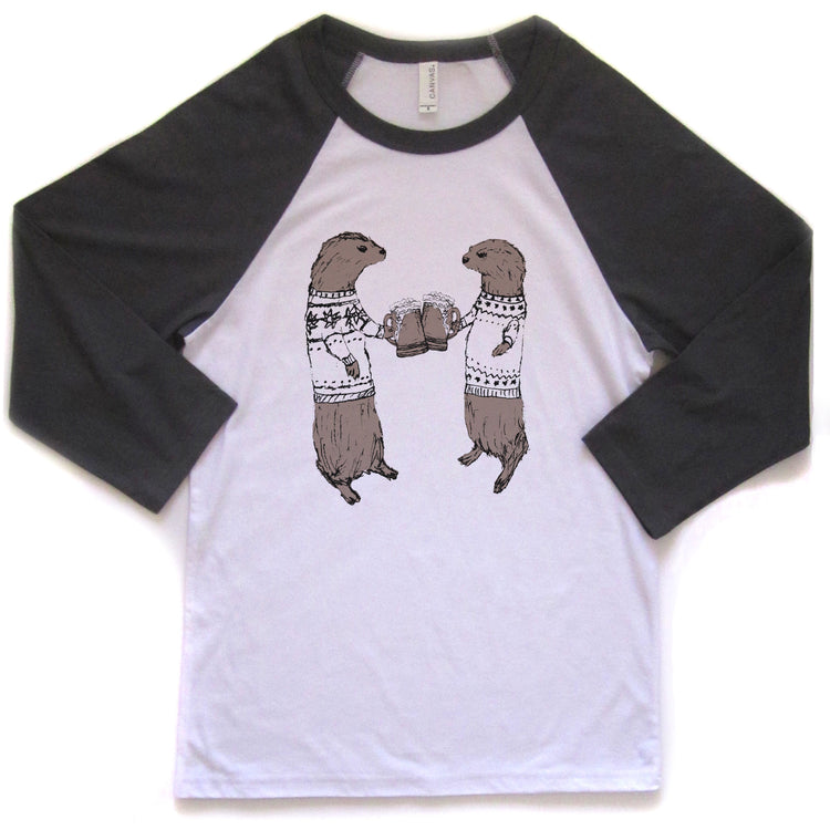 A white and black baseball-style t-shirt with a graphic design of two otters wearing sweaters and holding beer cans.