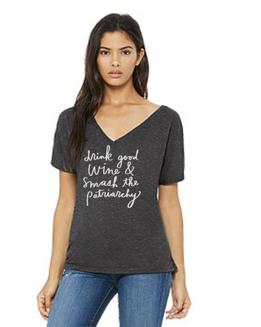 A woman wearing a gray t-shirt with the text "drink good wine & smash the patriarchy" printed on it.