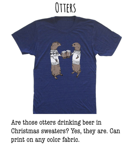 A blue t-shirt with a graphic of two otters wearing Christmas sweaters and holding beer mugs, along with text that asks "Are those otters drinking beer in Christmas sweaters? Yes, they are. Can print on any color fabric."