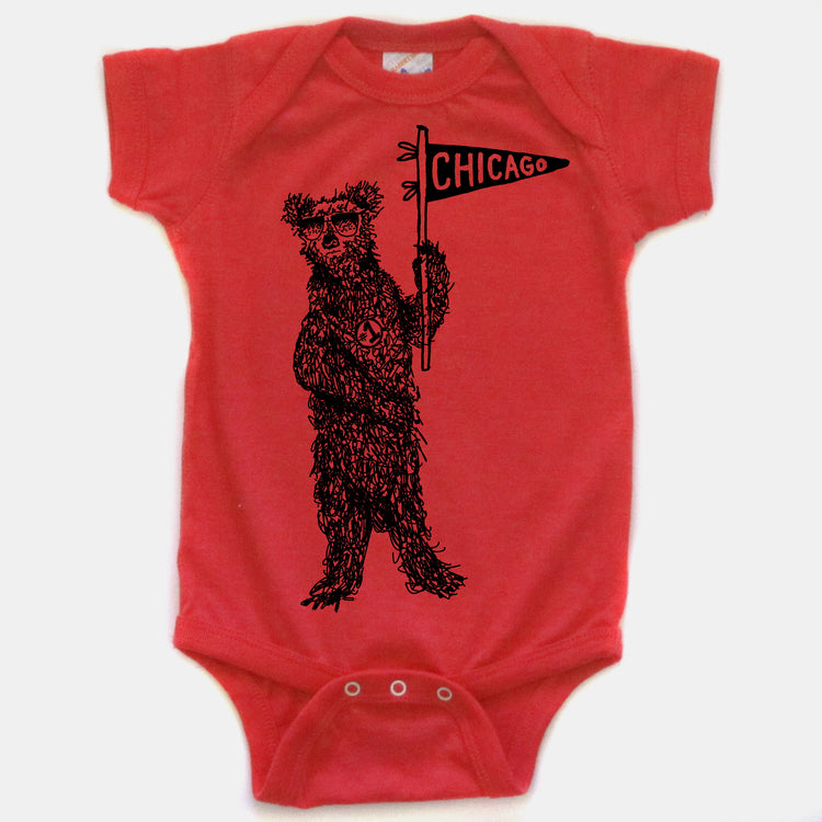 A red baby onesie with a black illustration of a bear holding a Chicago flag.