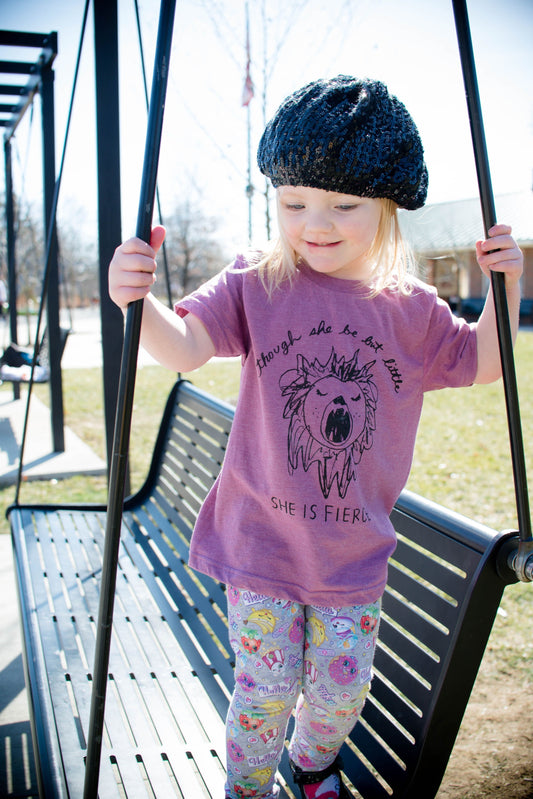 a little girl on a swing with a hat on