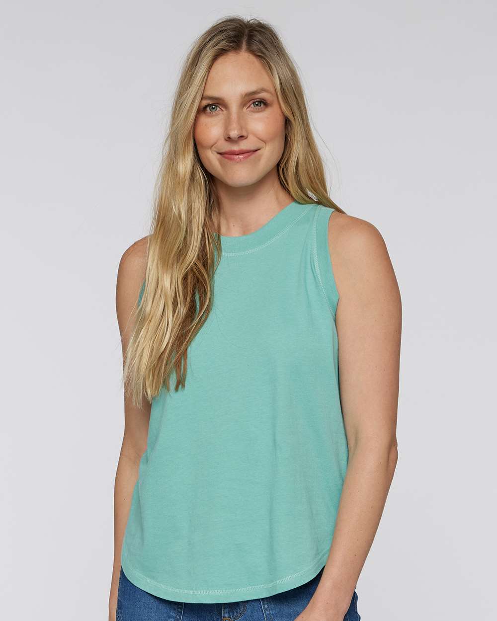 A woman with long blonde hair is smiling and wearing a turquoise sleeveless top.