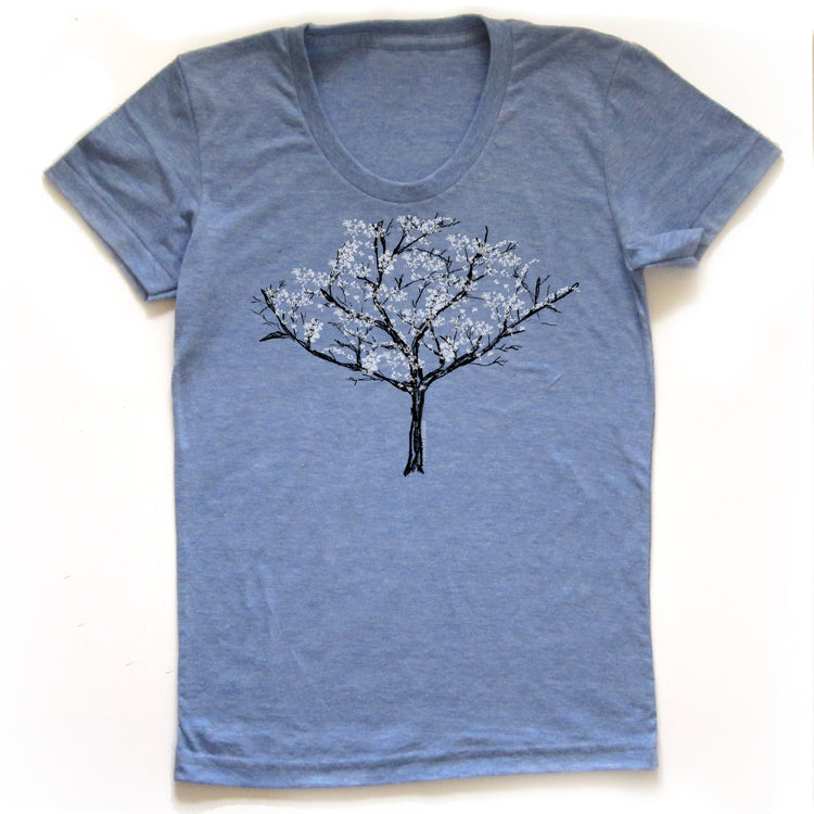 A blue t-shirt with a graphic design of a tree with white flowers printed on it.