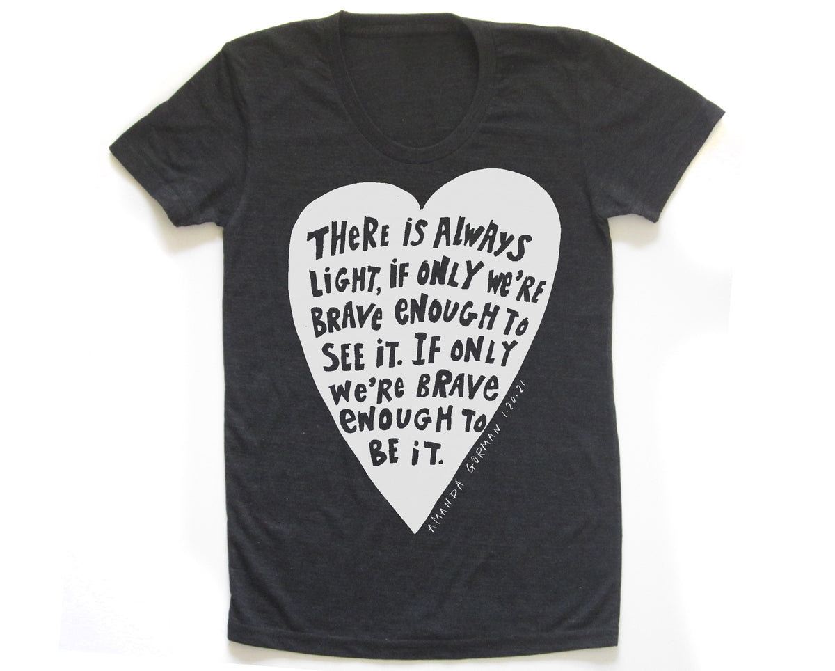 The image is a black t-shirt with a white heart-shaped graphic containing a quote in a black font.