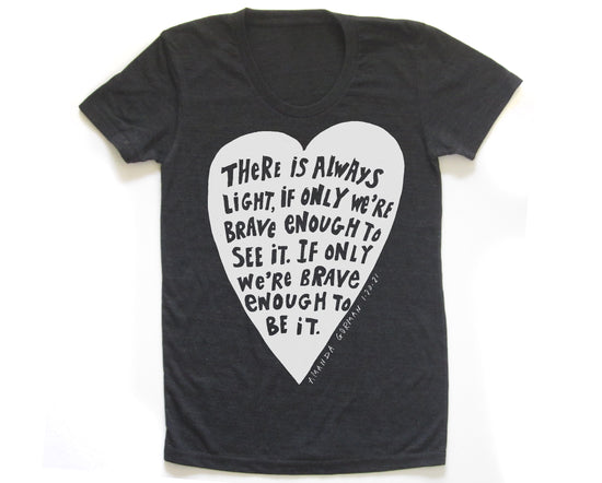 The image is a black t-shirt with a white heart-shaped graphic containing a quote in a black font.