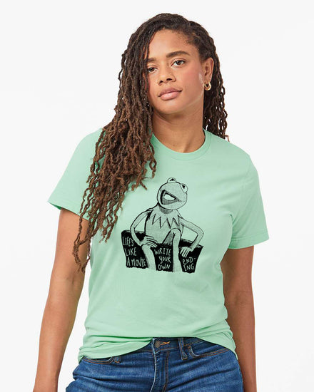 A young woman with dreadlocks wearing a mint green t-shirt with a graphic of Kermit the Frog and the text "Life's like a movie, write your own ending".