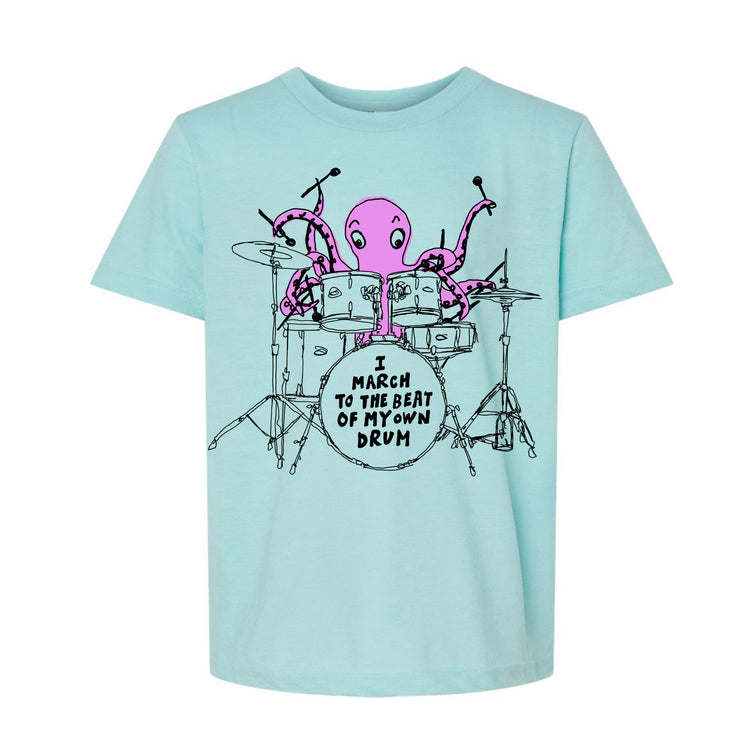 A light blue t-shirt with a graphic design depicting an octopus playing a drum set and the text "I march to the beat of my own drum" printed on it.