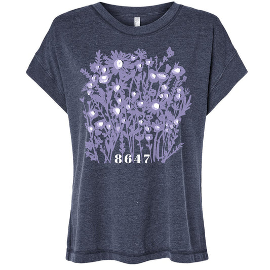 A gray t-shirt with a graphic design featuring a cluster of purple flowers and the number "8647" printed on it.