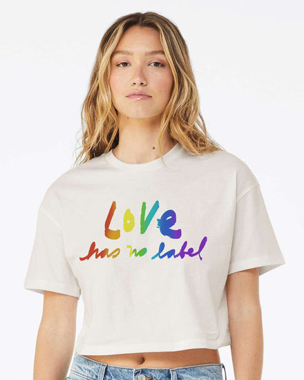 A young woman with long blonde hair wearing a white t-shirt with the text "Love has no label" printed on it.