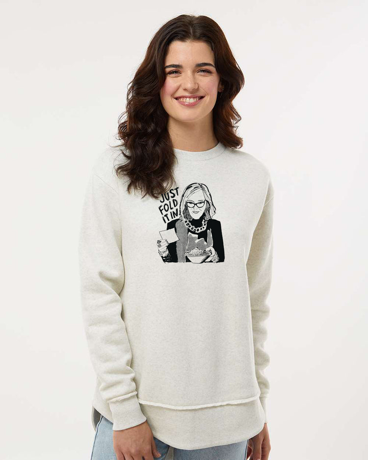 A smiling woman wearing a white sweatshirt with a graphic design of a woman holding a book.