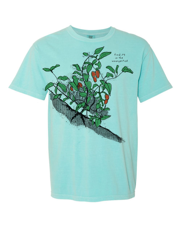A light blue t-shirt with a graphic design depicting a plant with green leaves and orange fruits.