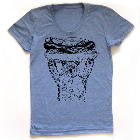 A blue t-shirt with a graphic design depicting a bear holding a hot dog on its head.