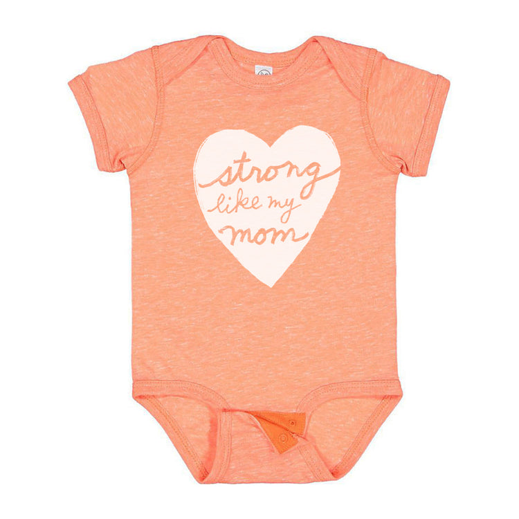 A peach-colored baby onesie with a heart-shaped graphic and the text "Strong like my mom" printed on it.