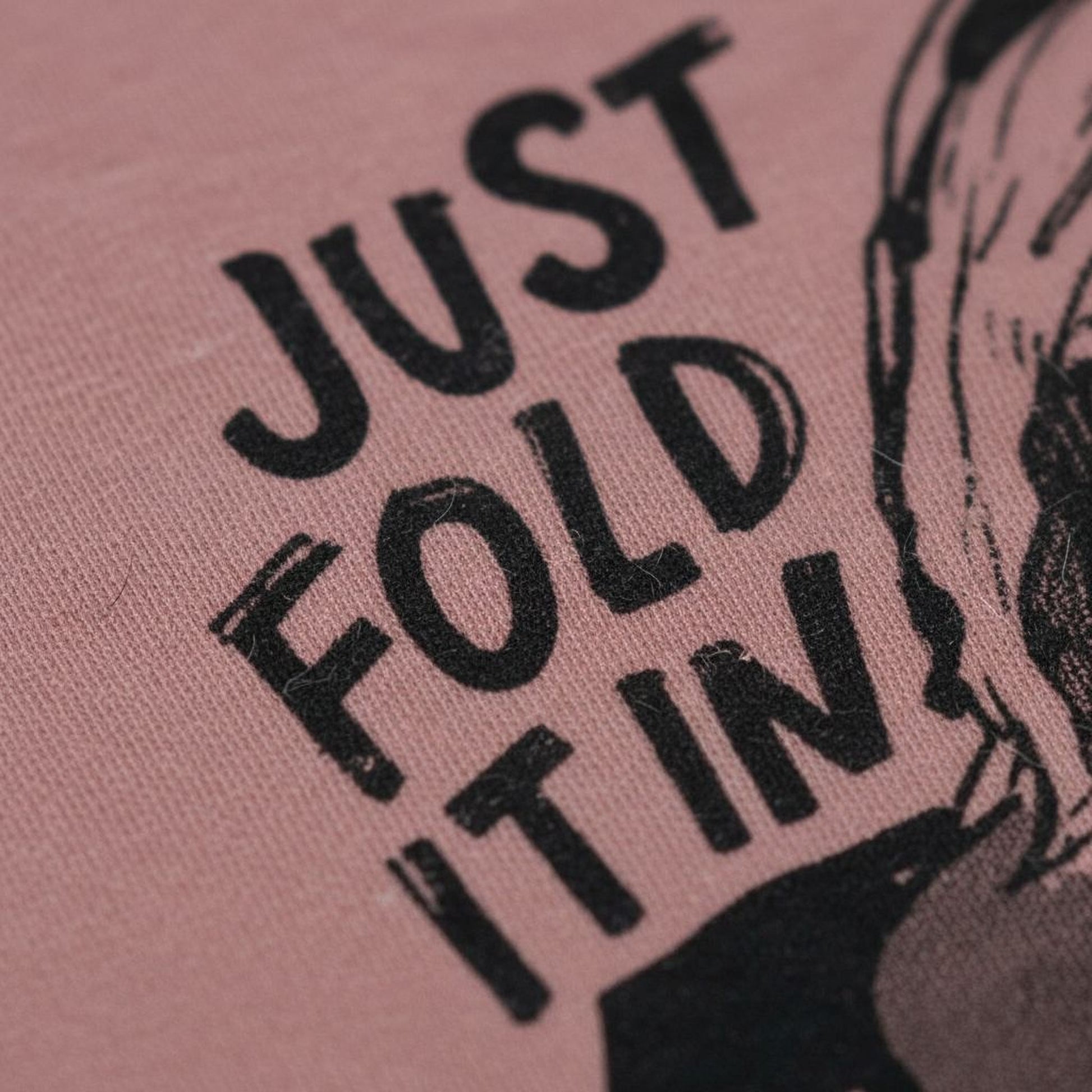 a close-up of a pink fabric with the text "JUST FOLD IT IN" printed on it.