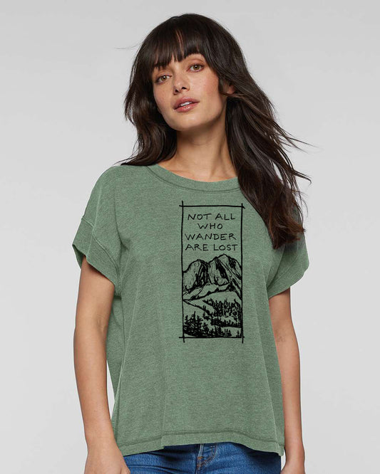a woman wearing a green t - shirt that says not all who wander are lost