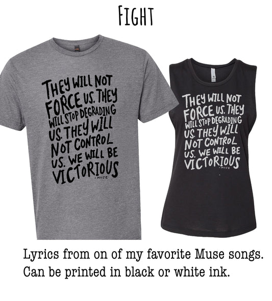 two t-shirts with black and white text printed on them. The text on the t-shirts reads "They will not force us. They will stopgrading us. They will not control us. We will be victorious." The t-shirts are described as "gray" and "black" in the provided text.