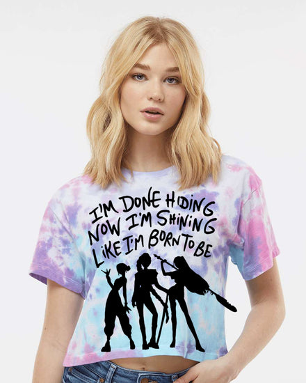 A young woman with blonde hair wearing a tie-dye shirt with a graphic design and text printed on it.