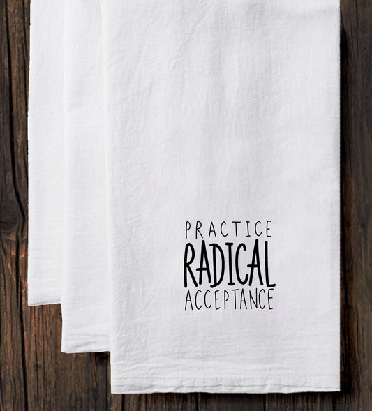 a set of white towels with black text printed on them. The text reads "Practice Radical Acceptance".