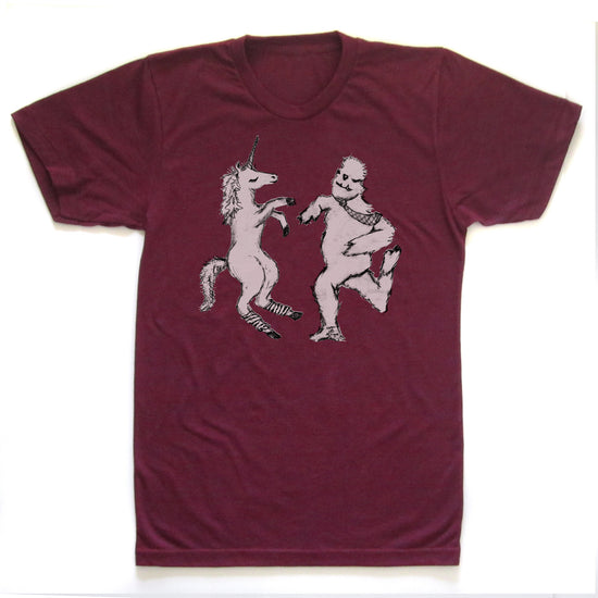 A burgundy-colored t-shirt with a graphic design depicting a unicorn and a creature resembling a Sasquatch or similar mythical being.