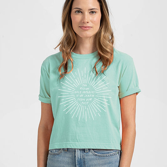 A woman wearing a mint green t-shirt with a white graphic design on it.