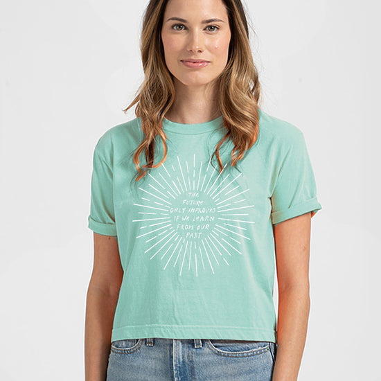 A woman wearing a mint green t-shirt with a white graphic design on it.