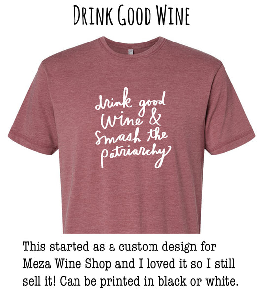 a red t-shirt with white text that reads "drink good wine & smash the patriarchy". The t-shirt is described as a custom design for Meza Wine Shop, and the person who created it loved it so much that they still sell it in black or white.