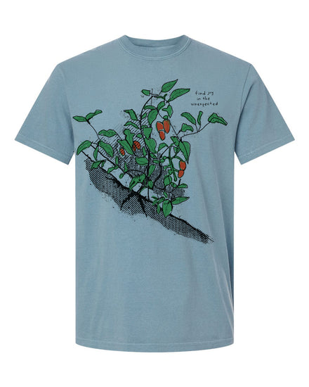 A light blue t-shirt with a graphic design depicting a plant with green leaves and orange fruits.