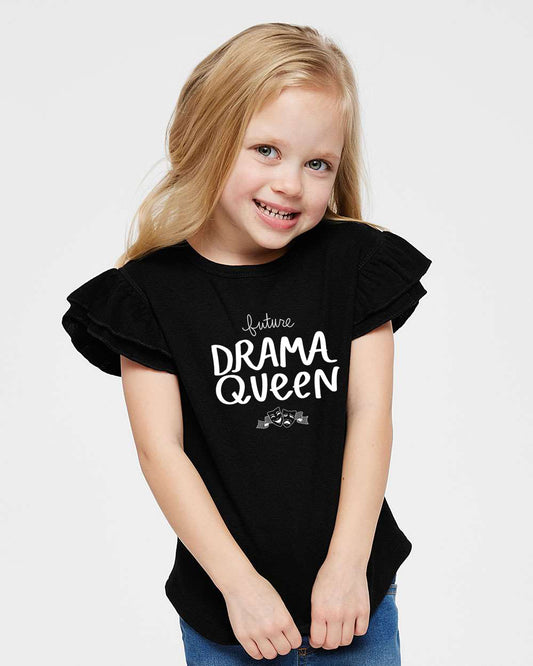 A young girl with blonde hair is smiling and posing for the camera, wearing a black t-shirt with the text "Future Drama Queen" printed on it.