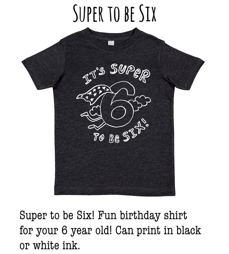A black t-shirt with a white graphic design that says "It's SUPER to be Six" and features a number 6 with clouds and lightning bolts.