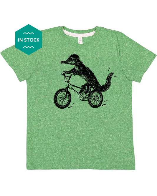 a green t - shirt with an alligator riding a bike