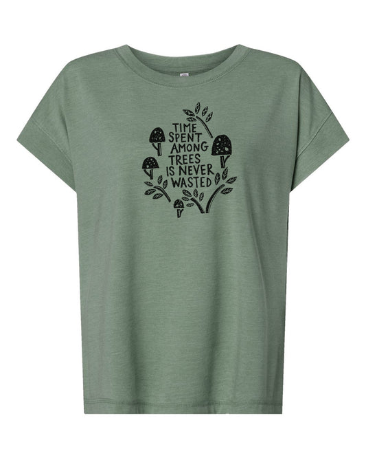A green t-shirt with a graphic design featuring a mushroom and leaves, along with the text "Time spent among trees is never wasted".
