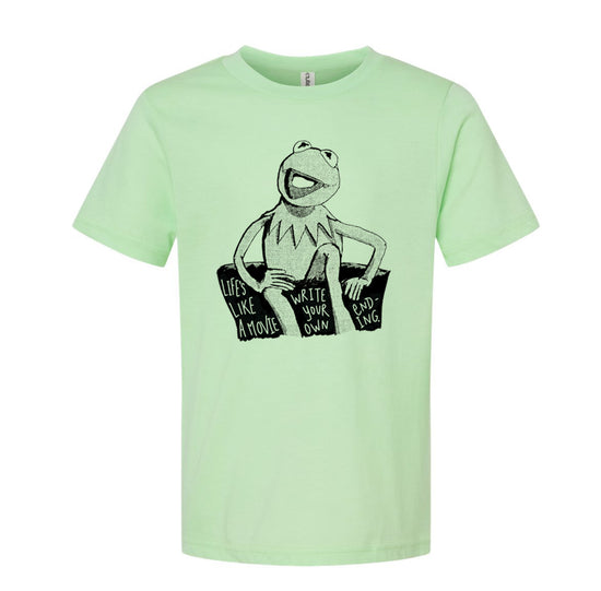 A light green t-shirt with a black and white illustration of Kermit the Frog sitting on a rock and the text "Lives like a movie, write your own" printed on it.