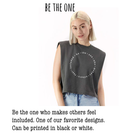 A woman wearing a gray sleeveless top with a white circular design on it, posing for a photograph.