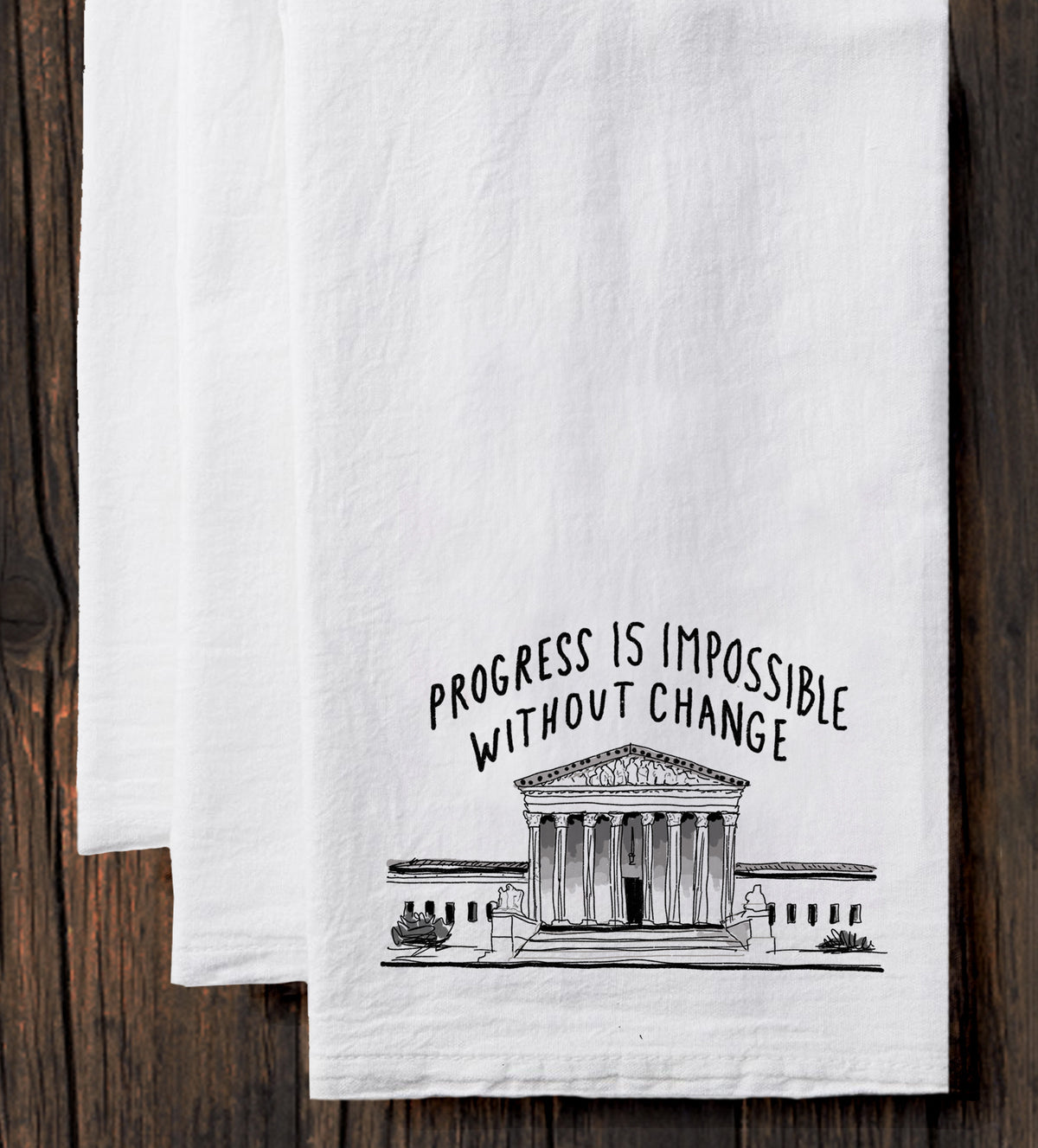 A white towel with a black and white illustration of a building and the text "Progress is Impossible Without Change" printed on it.