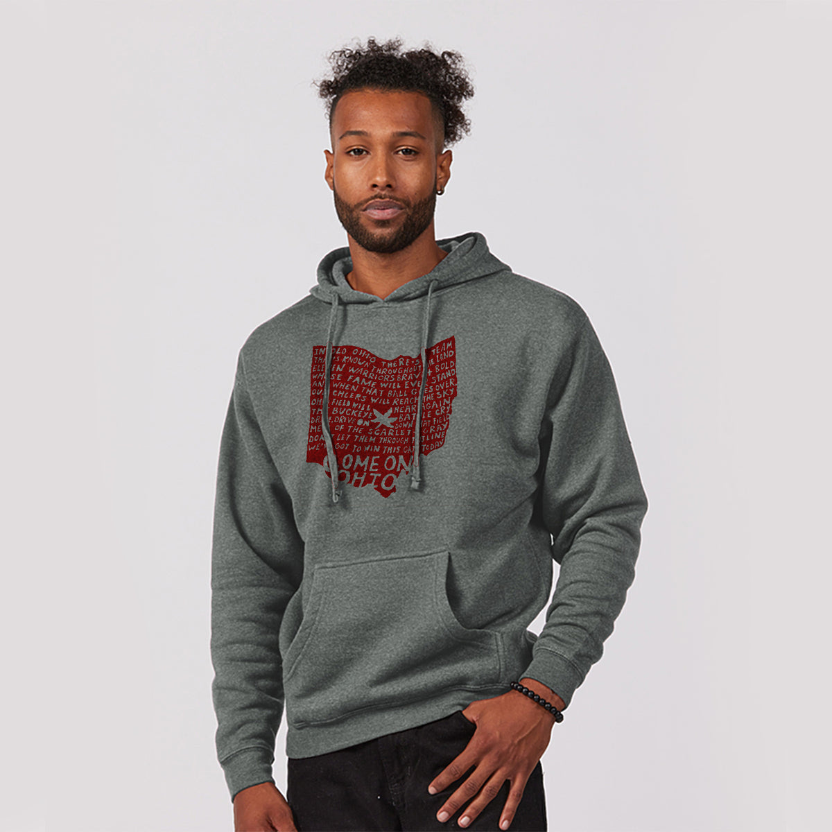 A man wearing a grey hoodie with a red graphic design on it, standing against a plain background.