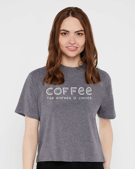 A woman with long brown hair wearing a gray t-shirt with the text "COFFEE THE ANSWER IS COFFEE" printed on it.