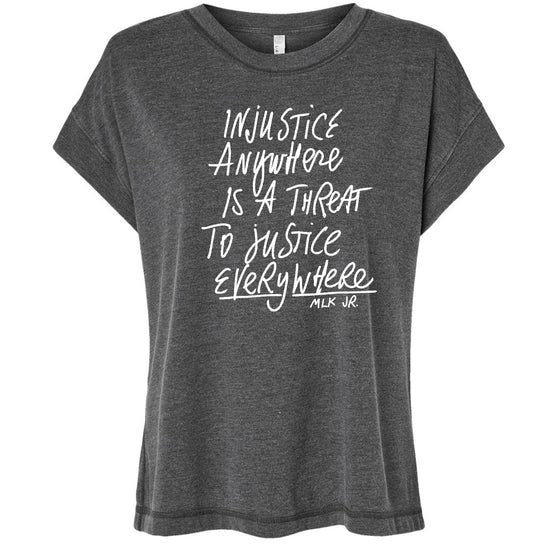 a gray t-shirt with white text printed on it. The text reads "Injustice anywhere is a threat to justice everywhere" and includes the name "MLK Jr."