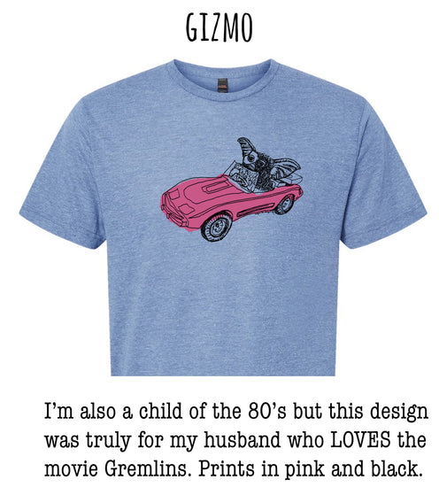 A blue t-shirt with a graphic design of a pink car with a winged creature on it, and text below the image that says "I'm also a child of the 80's but this design was truly for my husband who LOVES the movie Gremlins. Prints in pink and black."