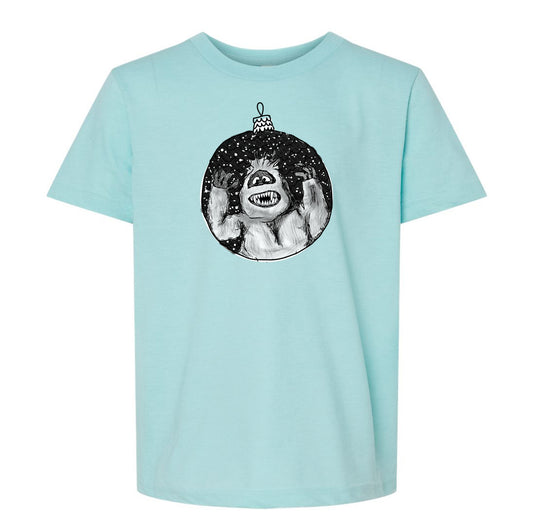 A light blue t-shirt with a graphic design depicting a monster or monster-like creature inside a circular ornament.