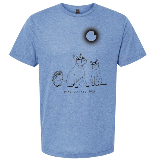 A blue t-shirt with a graphic design depicting a dog, hedgehog, and cat looking up at a black circle representing a total eclipse of the moon.