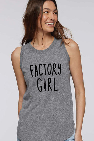 A woman wearing a grey tank top with the text "FACTORY GIRL" printed on it, smiling and looking to the side.